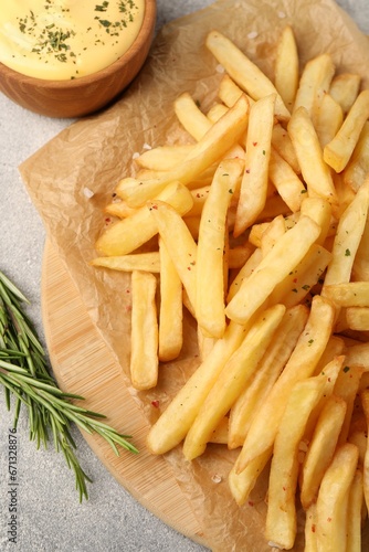 Delicious french fries served with sauce on grey textured table, flat lay