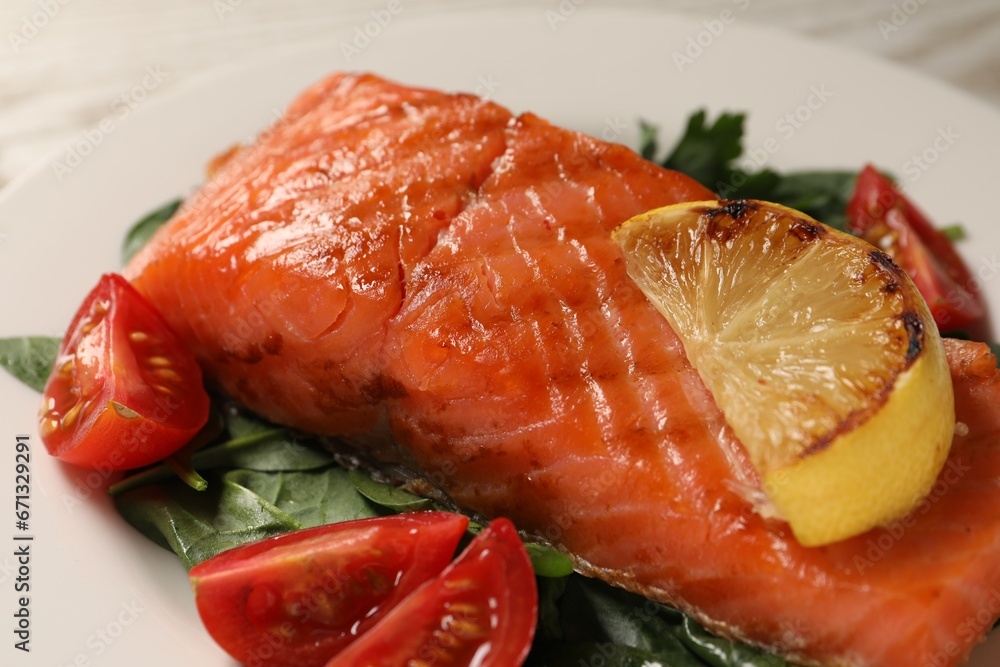 Tasty grilled salmon with tomatoes, lemon and basil on plate, closeup Tasty grilled salmon with tomatoes, lemon and basil on plate, closeup
