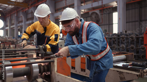 Fotografi A team of factory technician use a wrench to inspect the conveyor belt of the metal sheet production machine