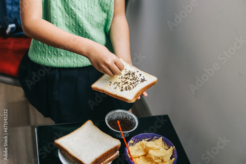 Asian school girl in making bread toast during breakfast time. photo
