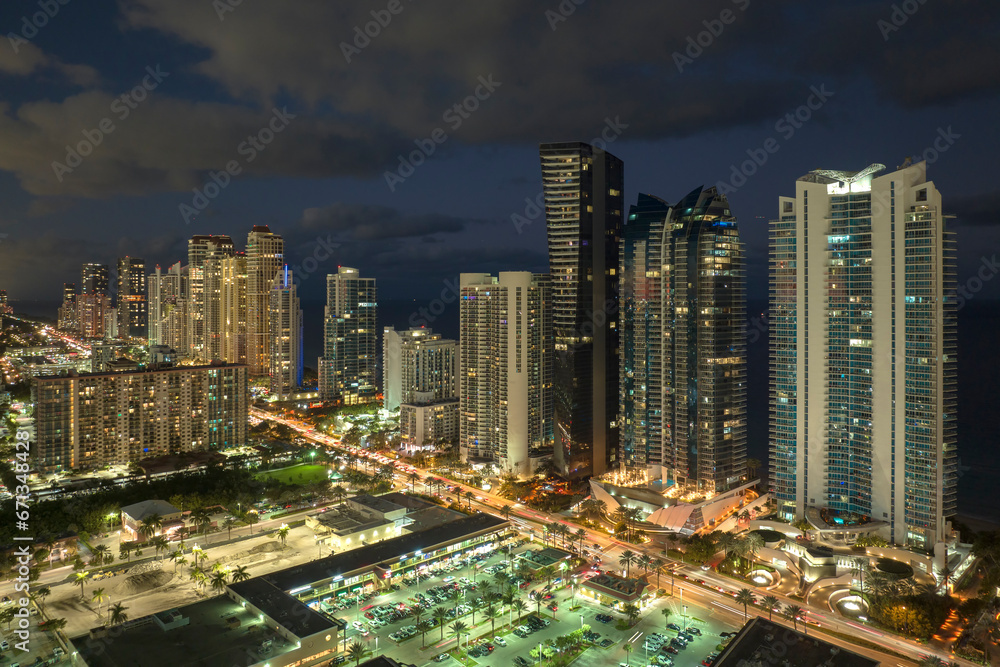 Obraz premium Aerial view of downtown district in Sunny Isles Beach city in Florida, USA. Brightly illuminated high skyscraper buildings in modern american midtown