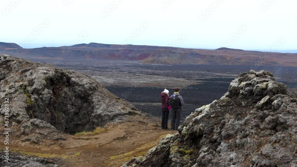 Aerial orbiting shot of a couple standing and looking out onto the scenery in Iceland Aerial orbiting shot of a couple standing and looking out onto the scenery in Iceland