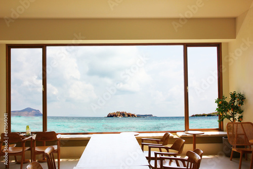 the living room design look at the panorama sea view. group of wooden chairs  table decoration in square room with big window open to sea blue sky white cloud