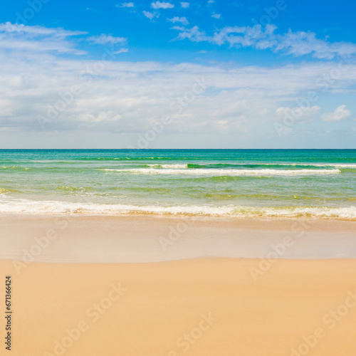 Beach with blue sky and clear water lapping the sand