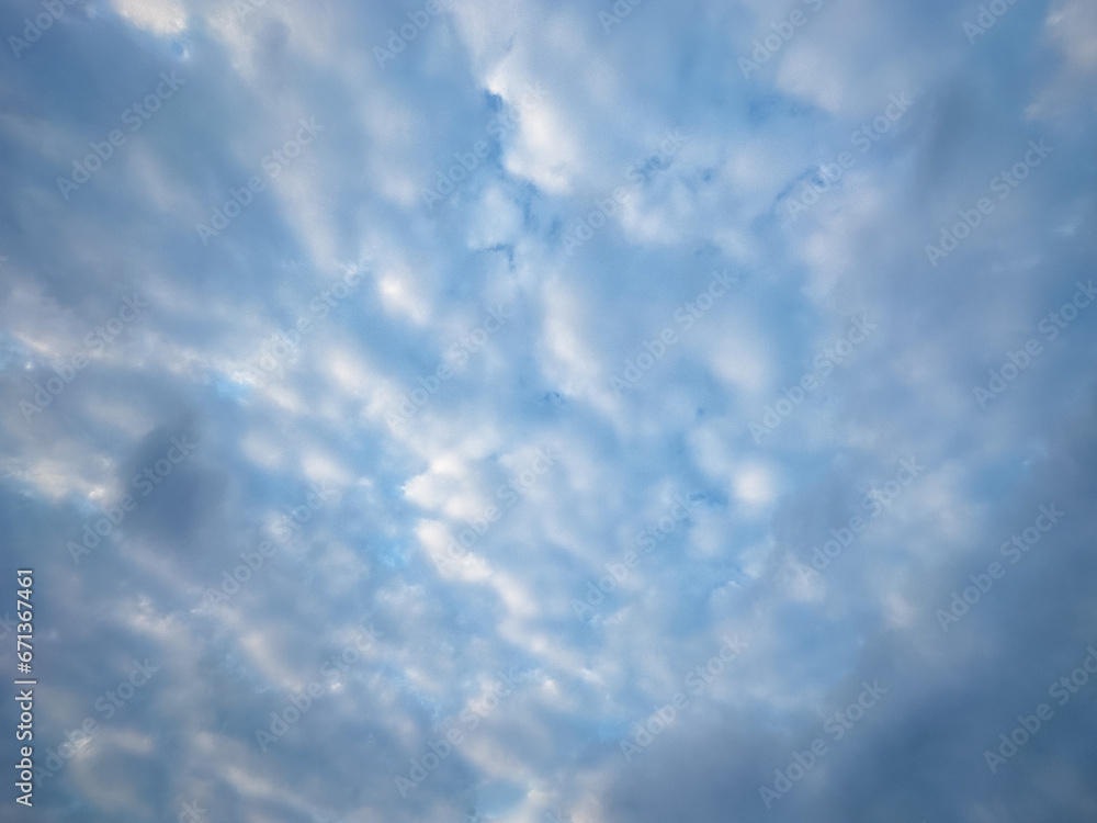 Blue sky with multitude small clouds texture pattern. A crowded background of tiny fluffy clouds for a design.