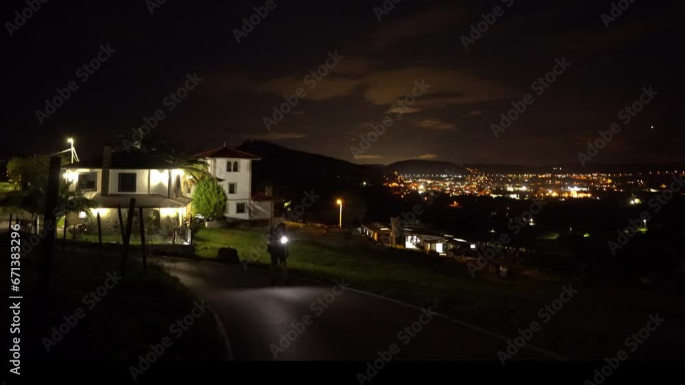 Walking man night hiking with flashlight view over illuminated city Walking man night hiking with flashlight view over illuminated city