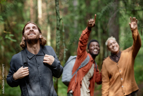 Group of happy friends looking up and smiling during their walk in the forest