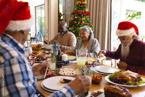 Happy diverse group of senior friends celebrating at christmas dinner in sunny dining room