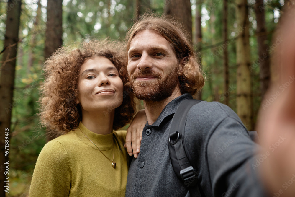 Selfie portrait of young couple smiling at camera during their hiking in the forest Selfie portrait of young couple smiling at camera during their hiking in the forest