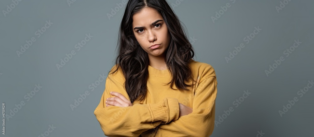 Unhappy and angry hispanic girl in casual attire with thumbs down gesture displaying rejection and negative emotion