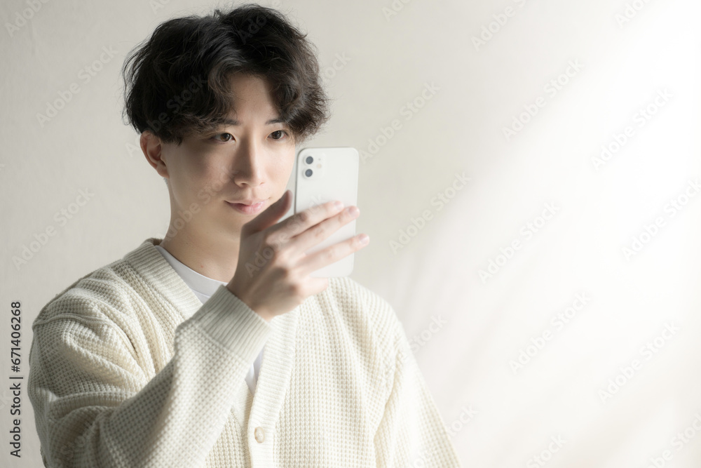 Asian man in knit looking at his phone Asian man in knit looking at his phone