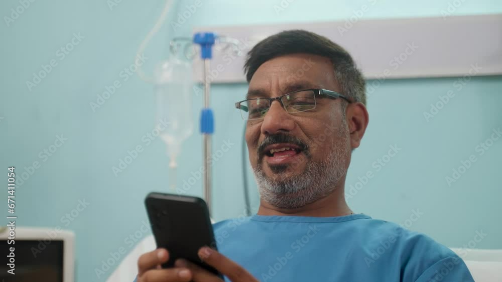 Indian Recovered happy Sick Senior patient using mobile phone at admitted hospital ward - concept of online interaction, medical treatment and health improvement Indian Recovered happy Sick Senior patient using mobile phone at admitted hospital ward - concept of online interaction, medical treatment and health improvement