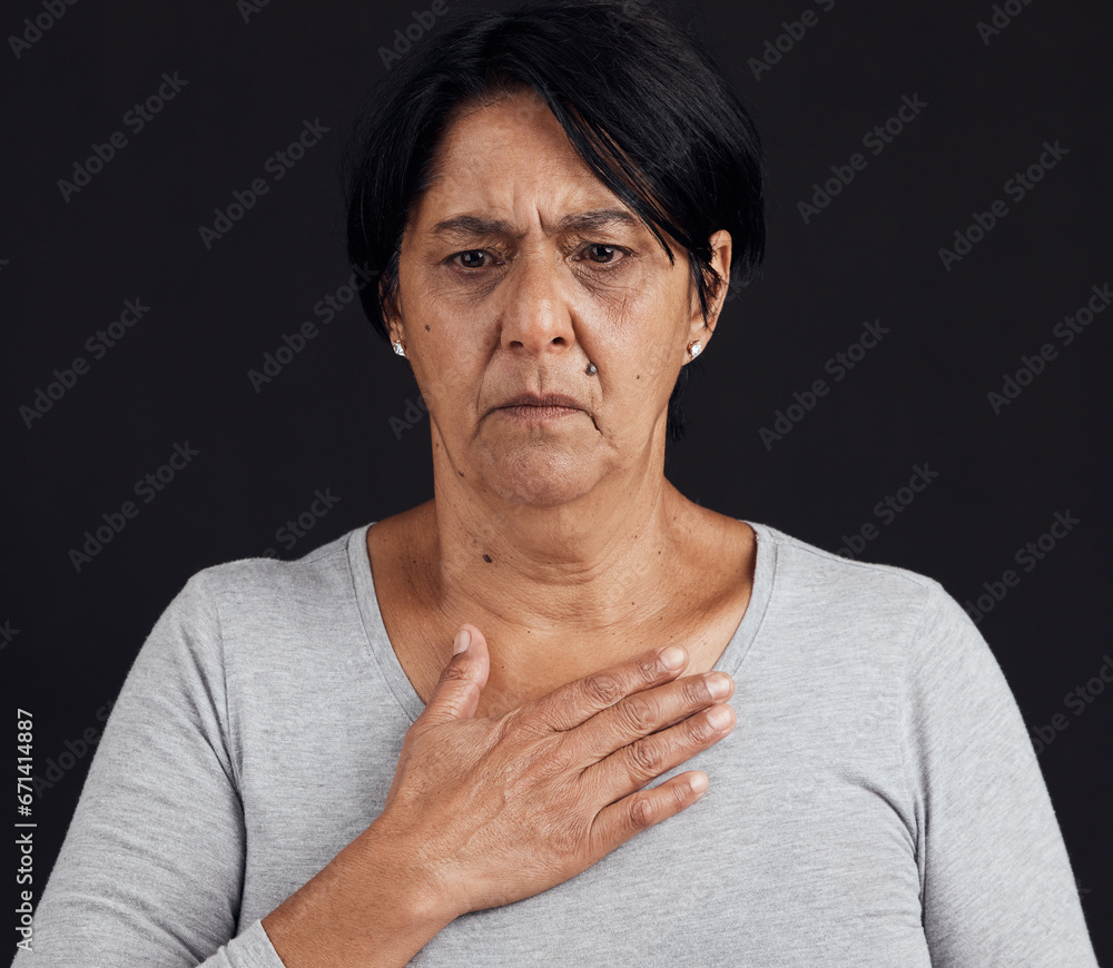 Fototapeta premium Fear, senior and a woman with a heart attack on a black background with healthcare anxiety. Emergency, sad and an elderly person feeling chest for pain, sick or medical scare isolated on a backdrop