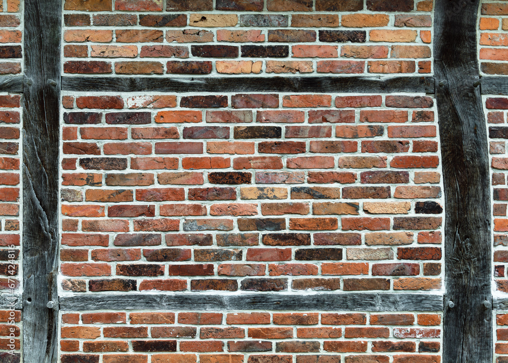 Weathered timber frame wall with bleached wooden beams and red brick stones. Background or texture. Weathered timber frame wall with bleached wooden beams and red brick stones. Background or texture.