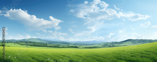 Beautiful natural scenic panorama green field of cut grass and blue sky with clouds on horizon. Perfect green lawn on sunny day