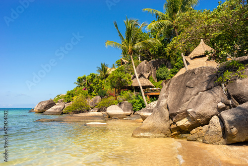 Scenic paradise sunny beach with stones and palms. Tropical sandy Sairee Beach with blue sky and clear sea water on Koh Tao Island in Thailand