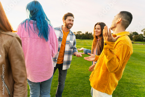 Group of attractive smiling multiracial friends talking, communication, meeting in green park. Festival, celebration, party concept 