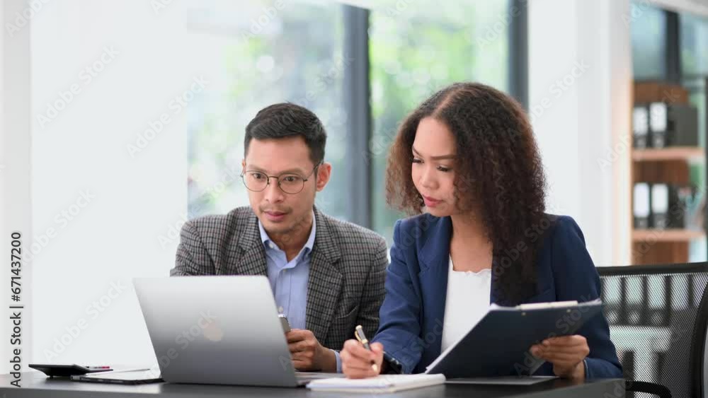Two business workers talking on the smartphone and using laptop at the office.. Two business workers talking on the smartphone and using laptop at the office..