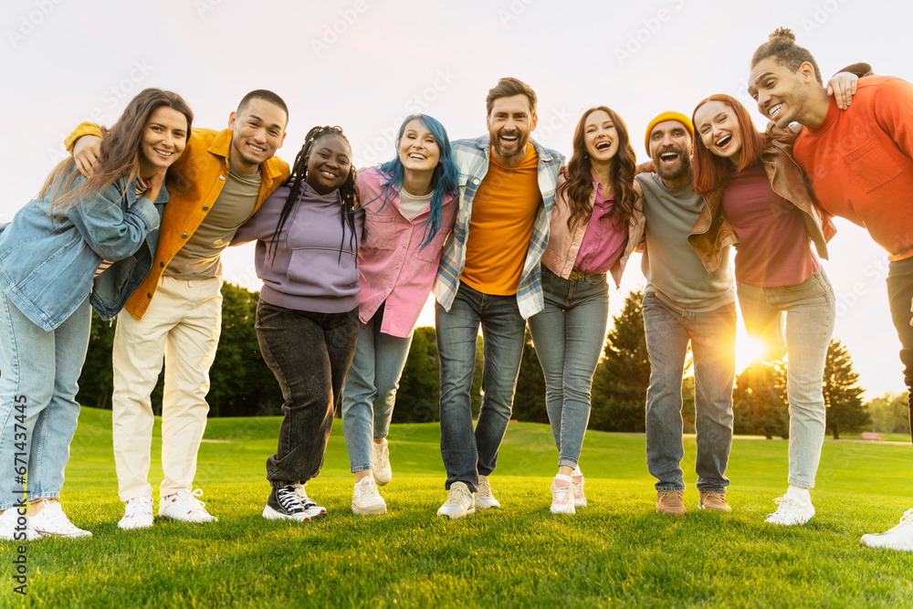 Group portrait of smiling international students hugging wearing looking at camera in university campus. Happy attractive multiracial friends standing together in green park. Diversity, friendship Group portrait of smiling international students hugging wearing looking at camera in university campus. Happy attractive multiracial friends standing together in green park. Diversity, friendship
