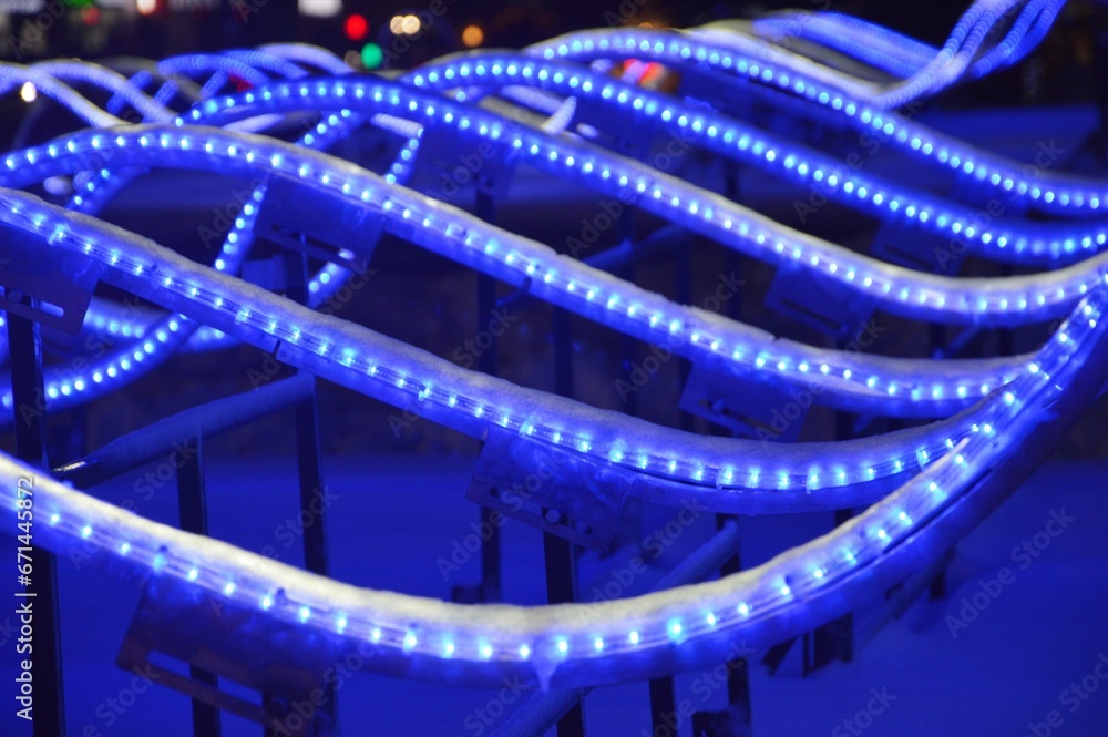 Glowing blue LED waves on a dark background. Element of Christmas light design of a city street at night.