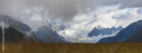 Photography Scenic landscape of rocky mountains covered in a blanket of fluffy clouds