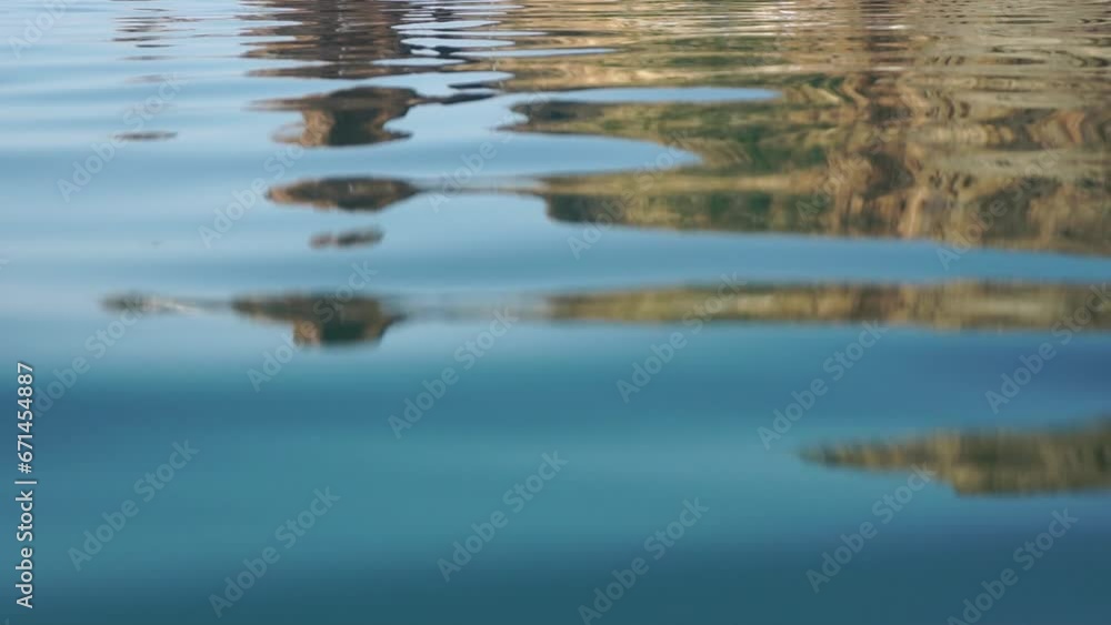 Sea water surface. Camera flies over the calm azure sea with volcanic rocky shores on background. Nobody. Holiday recreation concept. Abstract nautical summer ocean nature. Slow motion. Close up Sea water surface. Camera flies over the calm azure sea with volcanic rocky shores on background. Nobody. Holiday recreation concept. Abstract nautical summer ocean nature. Slow motion. Close up