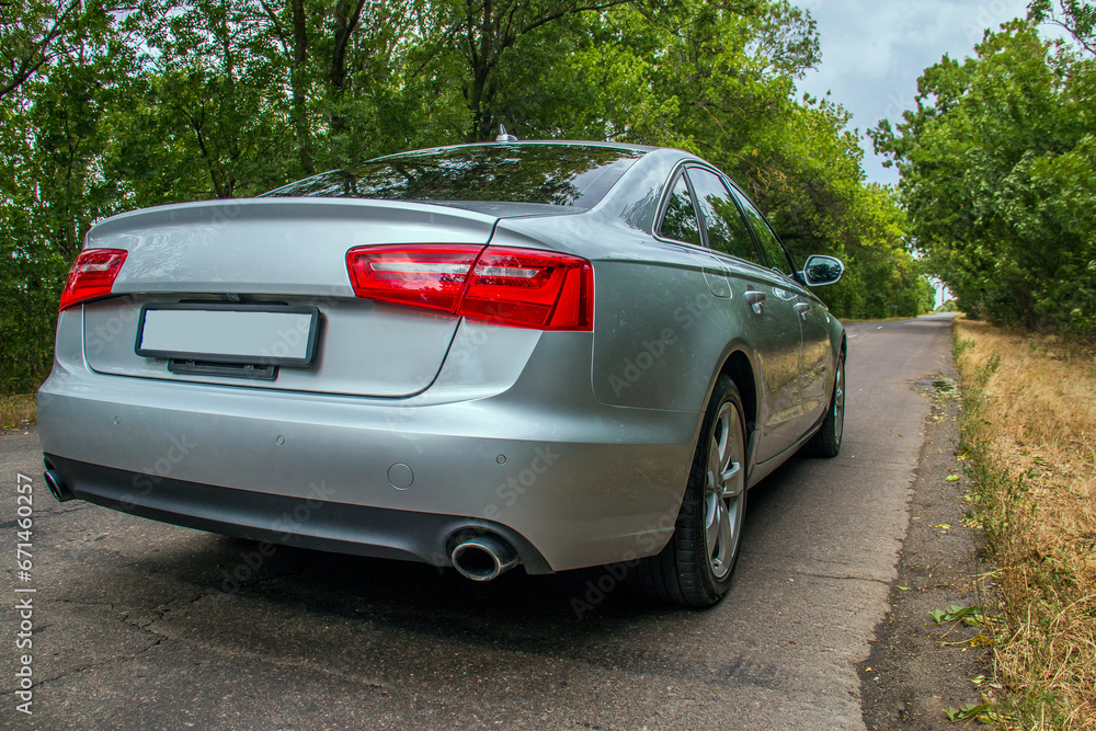 a gray car with two red headlights on the trunk stands along the road among the trees a gray car with two red headlights on the trunk stands along the road among the trees
