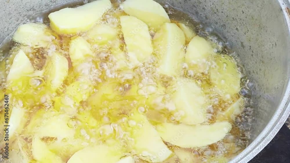 Cooking potatoes in a pot of boiling oil outdoors. Cooking fried potatoes in village slices. Cooking potatoes in a pot of boiling oil outdoors. Cooking fried potatoes in village slices.