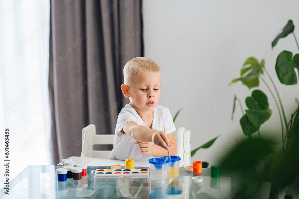 A cute boy draws with paints. Children draw in their free time A cute boy draws with paints. Children draw in their free time