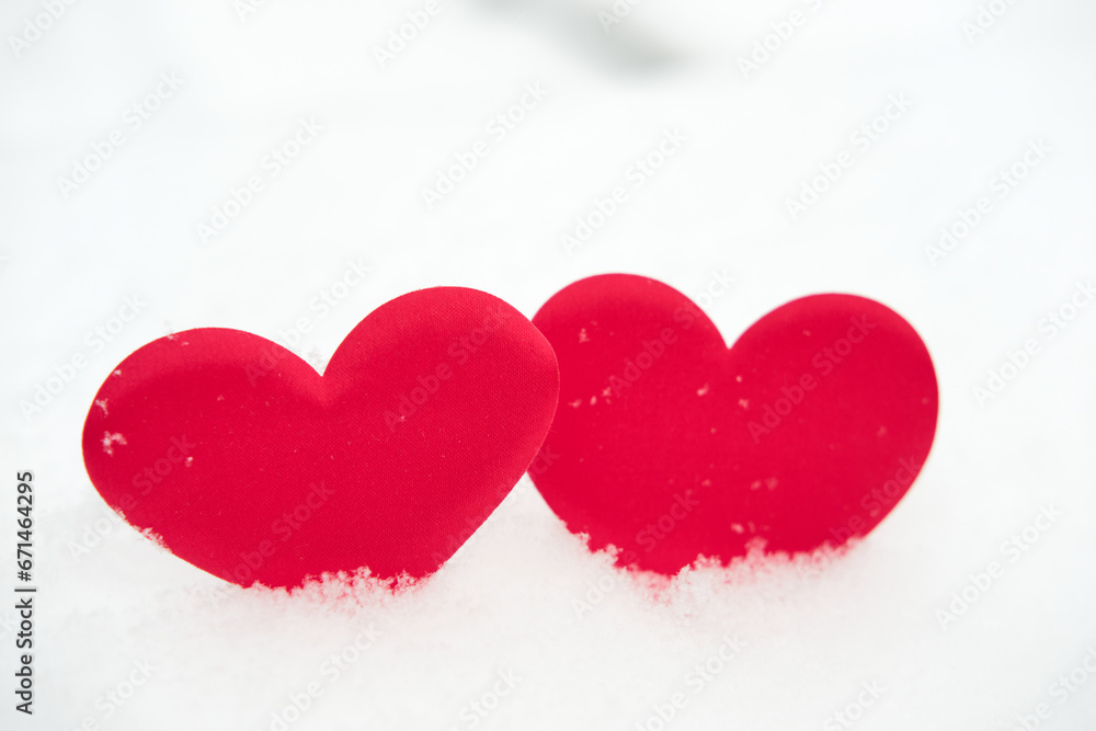 Two red heart shape on natural pure white soft snow surface side by side. Symbol of love in winter holiday season. Romantic outdoor concept for Valentine's day with copy space. front view, close up