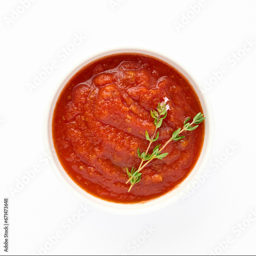 Red sauce from tomatoes and peppers for meat dishes in plate isolated on white background decorated with green sprig of parsley for your design top view. Healthy eating