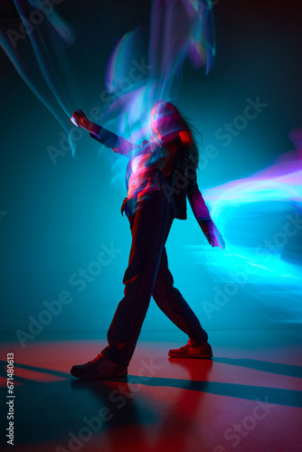 Surreal walk. Bottom view of young girl against blue background with mixed neon lights reflection. Concept of modern art, beauty, style, futurism and cyberpunk, creativity
