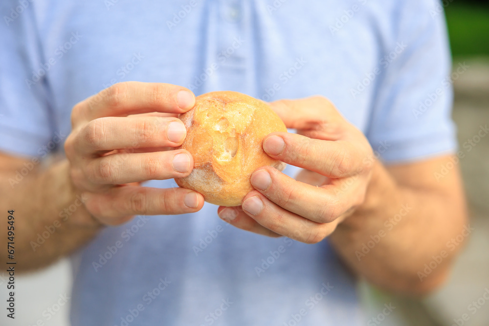 Guy's hand holds a round bun, snack and fast food concept. Selective focus on hands with blurred background Guy's hand holds a round bun, snack and fast food concept. Selective focus on hands with blurred background