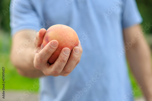A man's hand holds a peach, snack and fast food concept. Selective focus on hands with blurred background