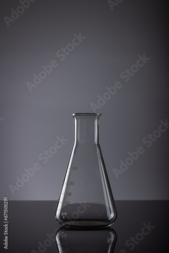 Vertical image of close up of laboratory beaker and copy space on grey background