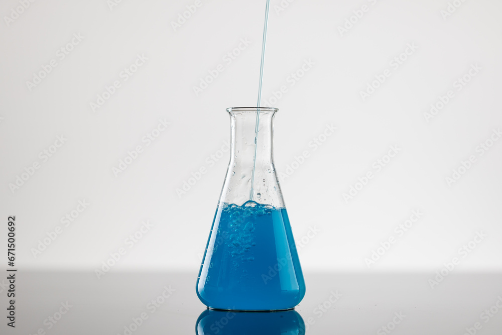 Close up of laboratory beaker with blue liquid and copy space on white background Close up of laboratory beaker with blue liquid and copy space on white background
