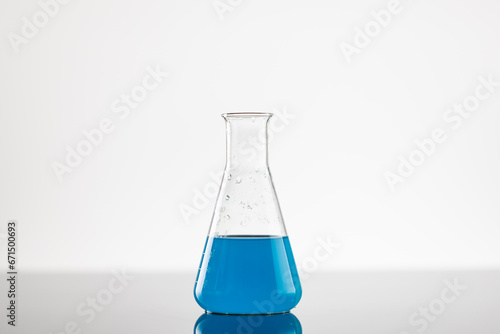 Close up of laboratory beaker with blue liquid and copy space on white background