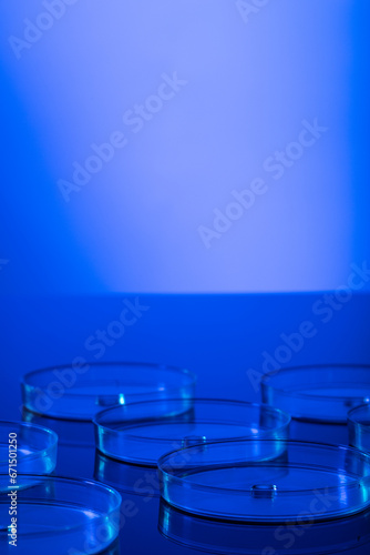 Vertical image of close up of laboratory dishes with blue liquid and copy space on blue background