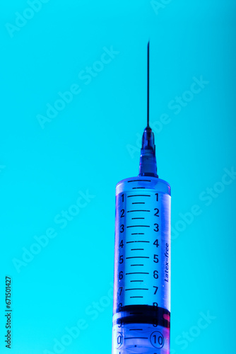Vertical image of close up of syringe with needle and copy space on blue background