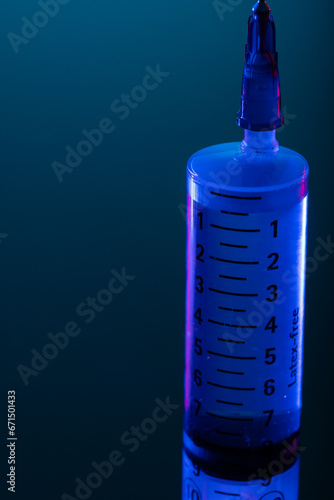 Vertical image of close up of syringe with needle and copy space on blue background