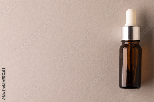 Brown glass bottle with pipette with copy space on brown background
