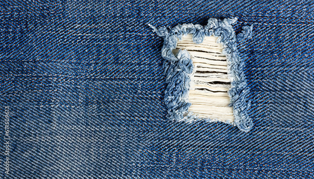 Blue jeans with a white stripe that has been torn off, Destroyed torn denim blue jeans texture, close-up rip in blue denim fabric, revealing white fabric underneath - obrazy, fototapety, plakaty 