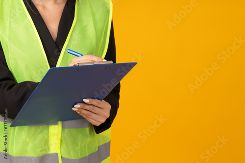 Folder and pen in female hands on yellow background, space for text