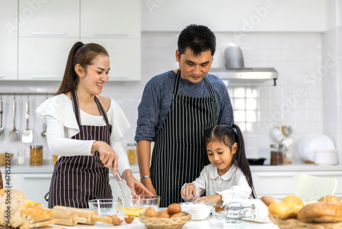 Portrait of enjoy happy love asian family father and mother with little asian girl daughter child play and having fun cooking food together with baking cookie and cake ingredient in kitchen