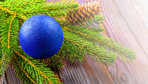 The Branches of a Christmas tree decorated with blue ball with silk on a wooden table