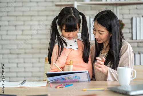 Portrait happy love asian family mother teach little daughter asian girl learn and study on table.Mom and asian young girl writing with book and pencil making lessons in homeschool at home.Education