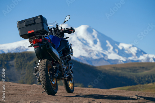 Traveling in the mountains off-road. A motorcycle on the background of a snow-covered volcano. Copy space.
