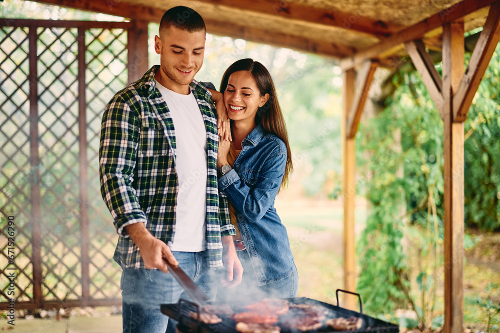 Two lovers having a barbecue together, spending time together outdoors, standing next to each other, looking lovely.