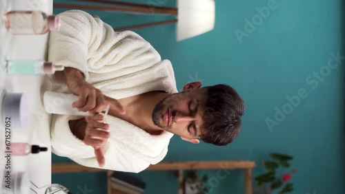 Arabic young attractive man applying protective cream on hands having daily beauty routine at home photo
