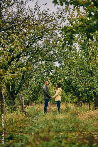 Photo of a beautiful couple standing in nature, looking at each other, holding hands.